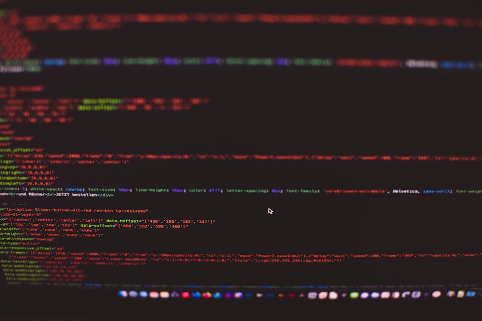 A close-up of a computer screen displaying colorful lines of code in red, green, blue, and purple on a dark background. The code includes HTML and CSS elements with visible tags, attributes, and style